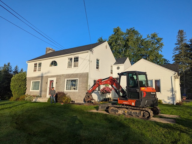 Using a mini excavator to remove old landscaping shrubs and bushes